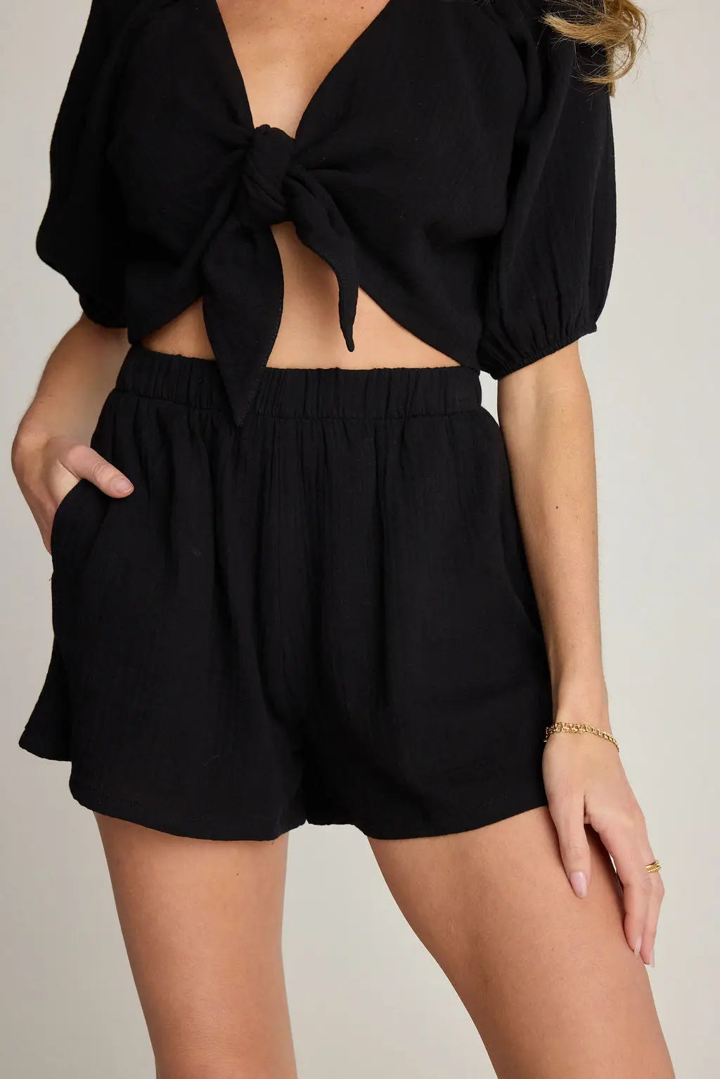 Lucia Shorts, front view showing the high waisted fit, elastic waistband, relaxed silhouette, and side pocket detail paired with a matching tie front crop top in a clean studio setting.