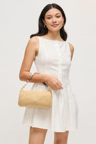 Model pairing the natural Rachel Straw Clutch with a day-to-night look, featuring a handwoven exterior, sculpted bead trim, and metallic hardware.