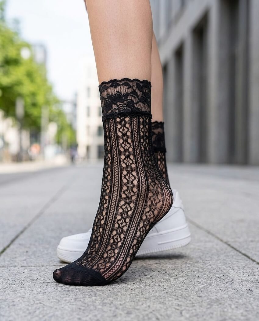 Floral Lace Vertical Fishnet Socks featuring a delicate openwork pattern with floral lace trim, worn with casual sneakers while standing on a city sidewalk, showcasing the stylish sheer texture, ankle length silhouette, and everyday fashion appeal.