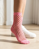 Midnight Lattice Fishnet Socks featuring an open fishnet lattice knit with a soft stretch crew fit and solid toe detailing, worn with white sneakers indoors on a sunlit wooden floor, highlighting breathable comfort and bold everyday street styling.