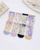 Floral Pattern Sheer Socks 4-Pack featuring translucent mesh fabric with assorted botanical prints, soft colored cuffs, and reinforced toe accents, displayed together on a clean white surface with lifestyle props, highlighting delicate floral style and lightweight everyday comfort.
