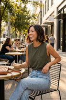Leah Top, sleeveless crew neckline tank top with a relaxed fit and chest pocket, shown in a candid outdoor café setting with high waist jeans, highlighting the clean armholes and soft drape in natural sunlight.