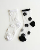 2-Pack Rosette Mesh Crew Socks featuring one white pair with white rosette embroidery and one black-trimmed pair with black rosette embroidery, displayed side by side on a clean white background, highlighting the sheer mesh construction and elegant floral detailing for versatile everyday styling.