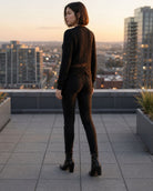 The Eloise Cardigan featuring a textured cable knit design with a scalloped lace hem, shown from the back on a rooftop, highlighting the detailed knit pattern and elegant lace trim.