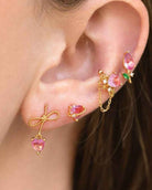 Blossoming Tulip Studs featuring pink teardrop crystal tulip detailing with delicate gold tone stems and leaf accents, styled in a layered ear stack with coordinating floral earrings, highlighting whimsical sparkle and botanical inspired jewelry styling.