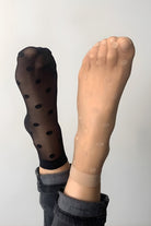 2-Pack Sheer Polka Dot Socks featuring a lightweight transparent knit with soft stretch fit and playful dotted pattern, shown on raised feet with one black and one nude pair side by side, highlighting contrast and a clean minimal indoor setting.