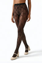 Fishnet Bow Tights featuring a sheer black fishnet design with crisscross diamond pattern and small bow accents, shown in a close front view with cream Mary Jane heels.