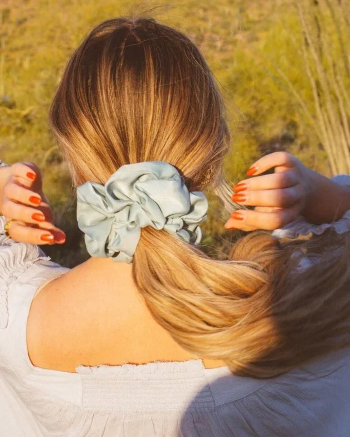 Back view of model wearing the Eucalyptus Jumbo Scrunchie in light blue green sateen fabric styled around a ponytail with oversized gathered volume.
