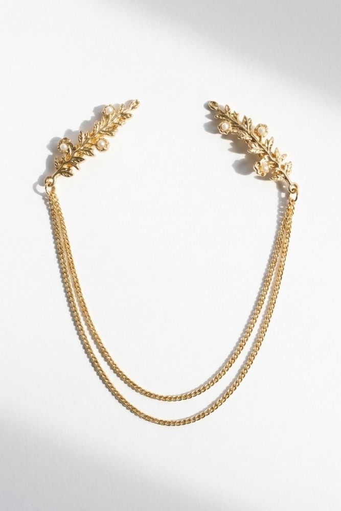 Bloom Bouquets Hair Chain featuring a delicate gold-tone hair accessory with leafy branch combs at each end, accented by small pearl-like details and connected by double draped chains, displayed on a clean white background to highlight its romantic, vintage-inspired elegance.