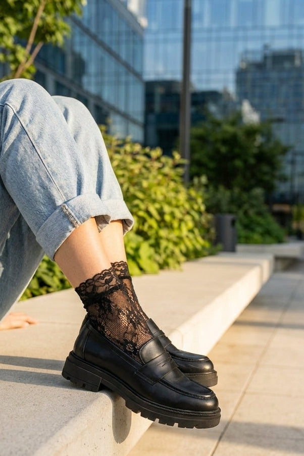 Romantic Floral Mesh Fishnet Socks in black featuring intricate floral lace detailing, paired with black loafers and rolled jeans on a sunlit city bench, showcasing the lightweight, semi-transparent fabric and elegant finish.