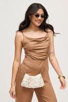 Model wearing an iridescent opalite evening bag with a glowing, color-shifting finish.