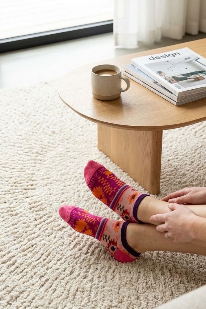 Shine Ultra-Short Ankle Socks featuring a soft, lightweight knit with bright floral and stripe detailing, worn while relaxing on a plush rug in a sunlit living space, emphasizing easy all-day wear and cheerful style.
