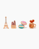 Café de Paris Stud Set, front product view showing Eiffel Tower, baguette bag, stacked macarons, and coffee cup studs in a polished gold tone with colorful enamel details.
