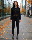 The Eloise Cardigan featuring a cable knit texture with a button-front closure and delicate lace hem, worn with dark jeans in a city setting, highlighting its refined silhouette and intricate knit detailing.
