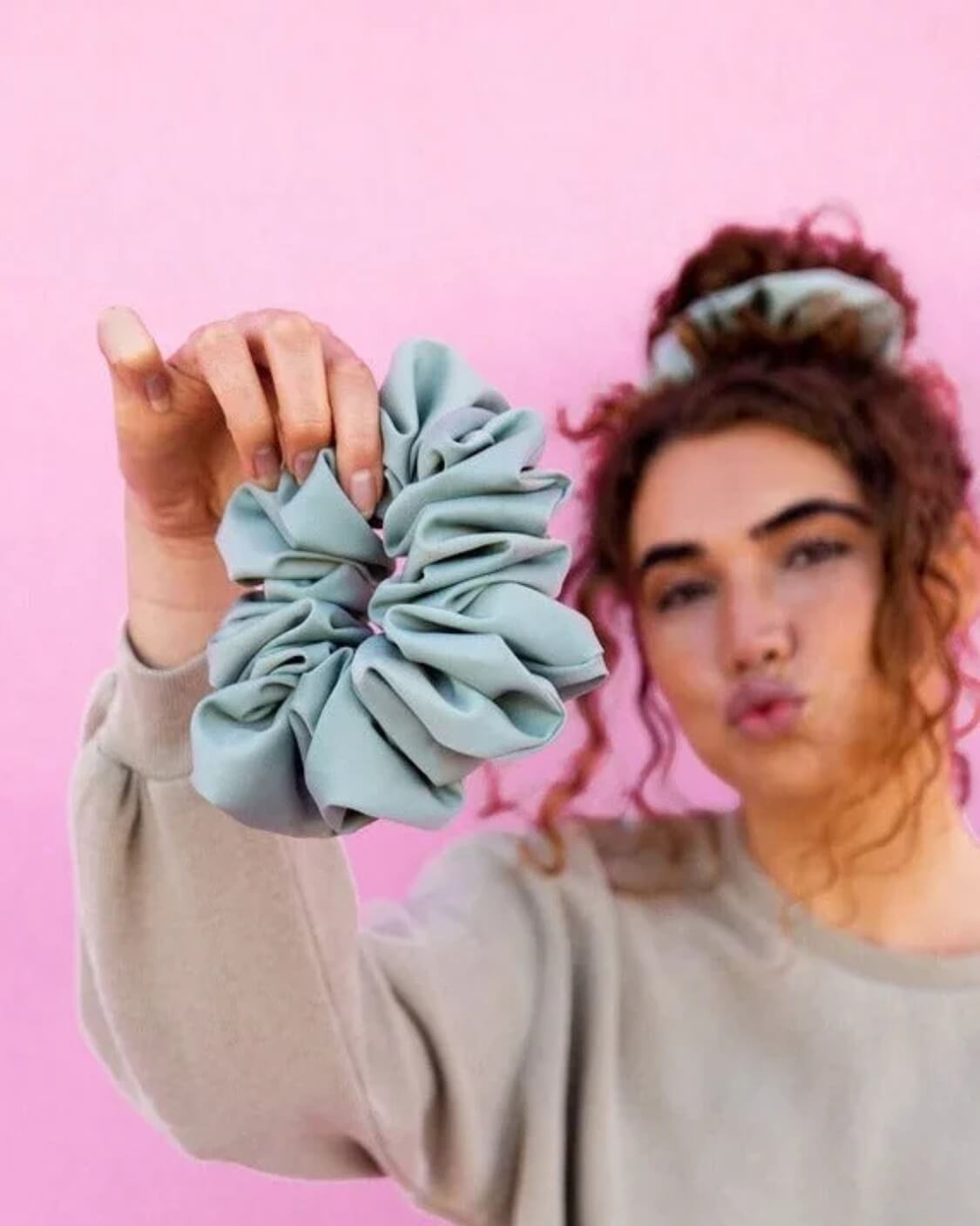 Model styled with the Eucalyptus Jumbo Scrunchie on a pink background highlighting the jumbo silhouette and smooth matte sateen texture.