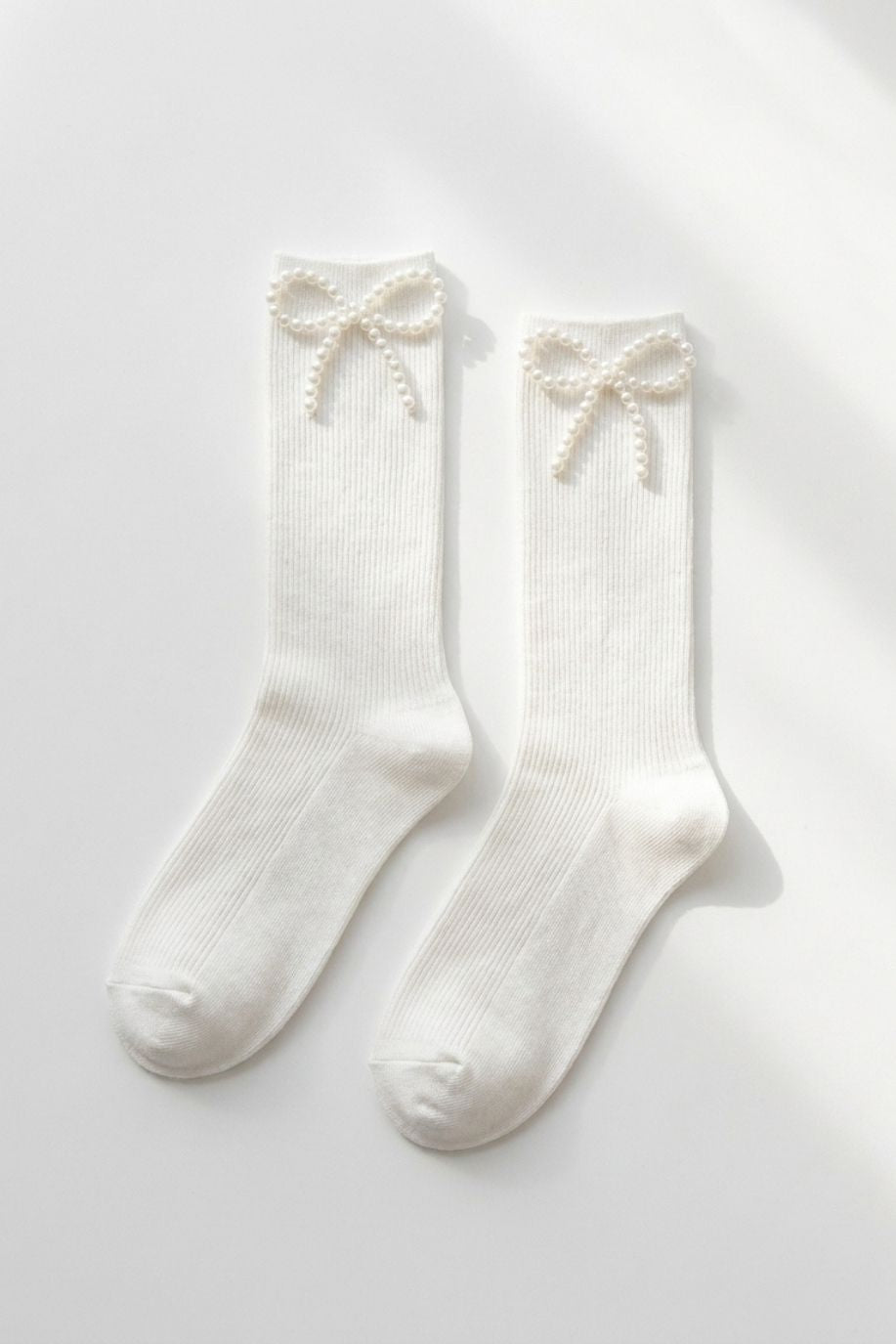 Pearl Bow Classic Ribbed Crew Socks featuring a soft ribbed knit with a pearl bow accent at the cuff, shown as a flat lay in white on a bright clean background, highlighting the elegant trim and timeless crew sock shape.
