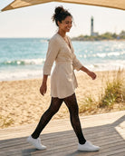 Natori Feather Pattern Net Tights featuring an all-over feather net pattern with a smooth fitted finish, worn with a belted tunic and sneakers on a seaside boardwalk, highlighting casual styling with light movement and visual texture.