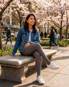 Lightweight Semi Opaque Tights in gray, featuring a lightweight semi-opaque knit and even coverage, styled with a denim jacket and sneakers, shown on a model seated on a park bench under blooming trees.