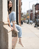 Midnight Lattice Fishnet Socks featuring an open mesh fishnet design with flexible stretch construction and solid cuff trim, worn with rolled denim jeans while seated on a city sidewalk ledge, highlighting breathable comfort and contemporary streetwear styling.