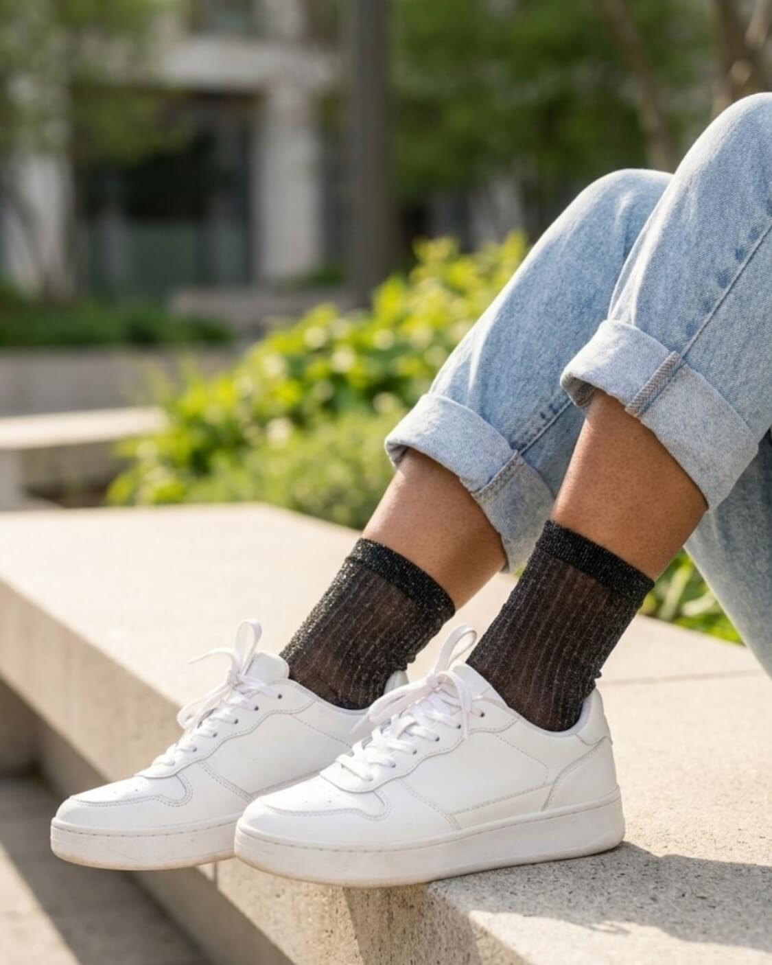 Sheer Metallic Ribbed Crew Socks in black with fine sparkle finish, paired with cuffed denim and white sneakers on outdoor steps, emphasizing the soft stretch fit and delicate ribbed detailing.