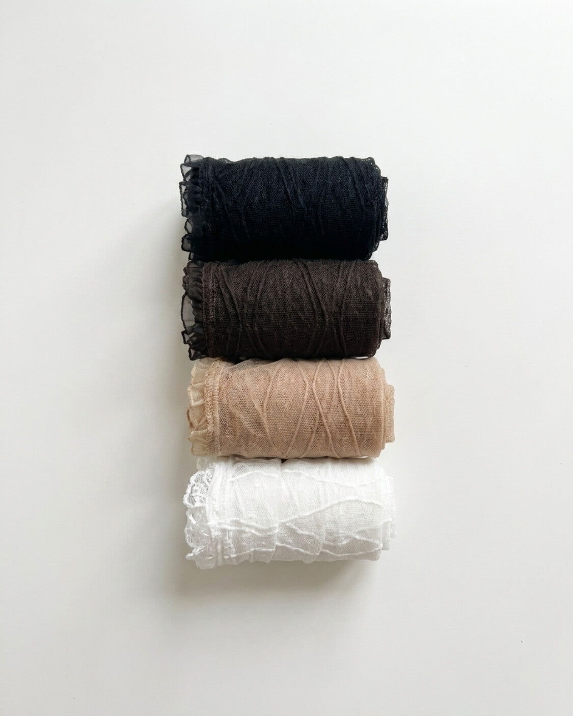 Bundled Packs Rosalie Lace Sheer Socks featuring raised wavy lace texture and delicate ruffled trim, stacked neatly in rolled layers on a clean white background, highlighting the assorted pack variety and soft sheer appearance.