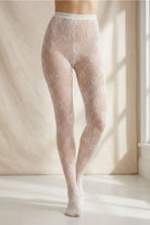 Sheer Floral Lace Tights featuring a delicate floral pattern and high waist design, styled in a bright indoor setting, highlighting the seamless fit and elegant leg silhouette.