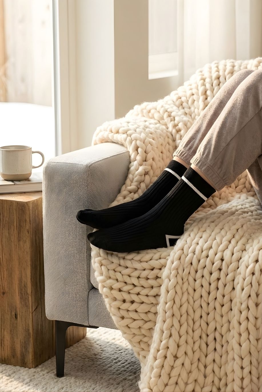 Classic Ribbed Crew Socks with Contrast Trim, black ribbed crew socks with white contrast trim worn with neutral loungewear, resting on a sofa with a chunky knit throw, emphasizing comfort and everyday wear styling.