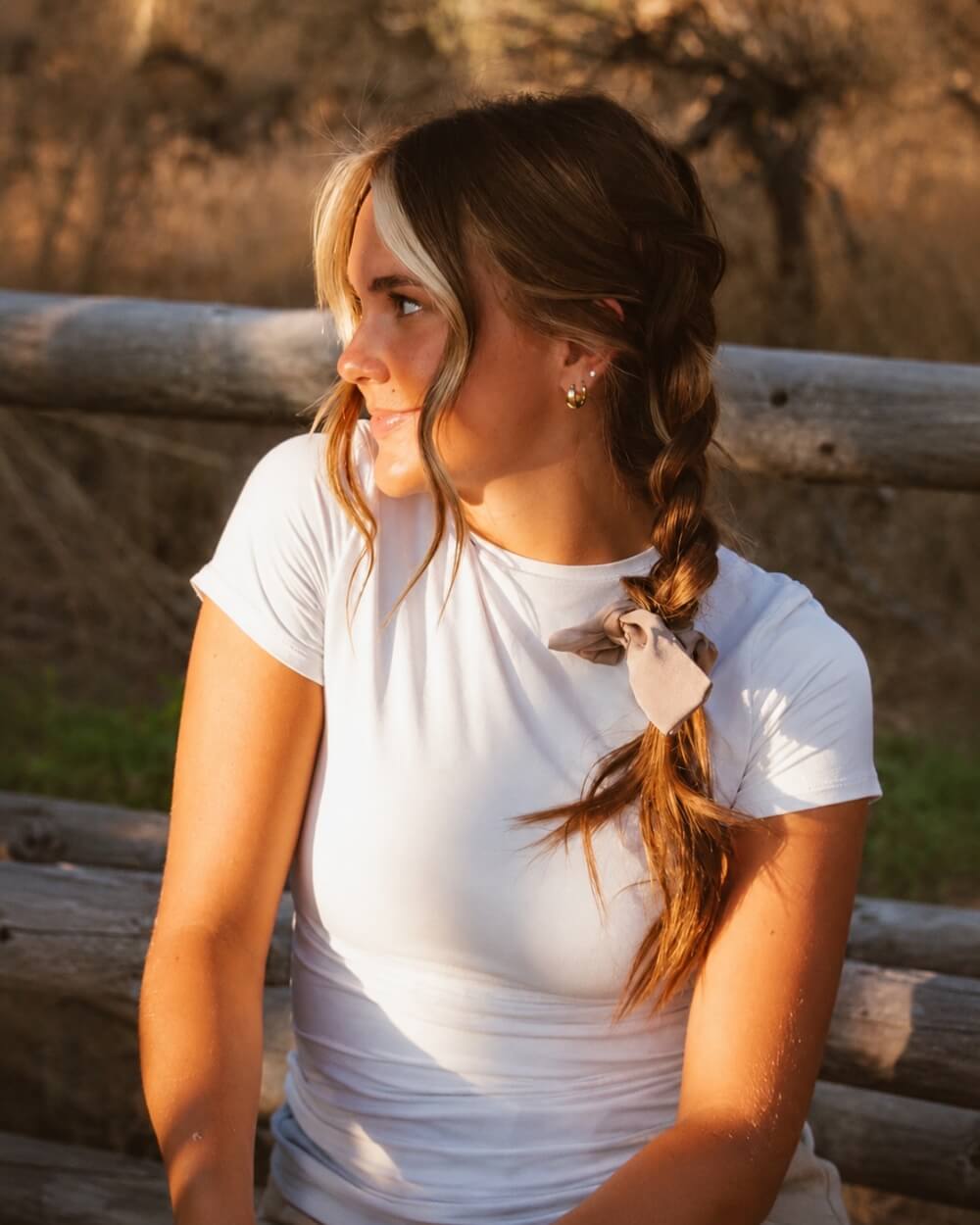 Model styled with the Chestnut Bow Scrunchie in a centipede hairstyle showcasing the elegant bow accent and smooth creamy brown sheen.