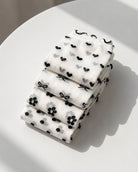 4-Pack Geo Print Ruffle Edge Sheer Socks featuring a coordinated collection of transparent mesh socks with geometric dot, heart, bow, and floral patterns, neatly folded and stacked on a minimalist surface to emphasize lightweight fabric, compact storage, and versatile everyday wear.