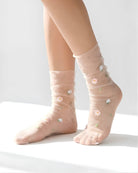 Sheer Garden Daisy Crew Socks in blush nude mesh with embroidered daisy flowers, shown on crossed legs against a clean light background to highlight the transparent fabric.