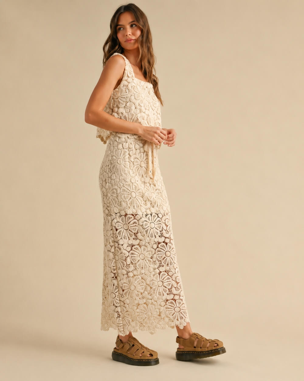 Crochet Knitted Skirt featuring detailed open floral crochet stitching with a relaxed straight fit and adjustable waist tie, shown in a side profile pose with woven platform sandals in a warm neutral studio setting, emphasizing airy texture and casual elegance.