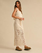 Crochet Knitted Skirt featuring detailed open floral crochet stitching with a relaxed straight fit and adjustable waist tie, shown in a side profile pose with woven platform sandals in a warm neutral studio setting, emphasizing airy texture and casual elegance.