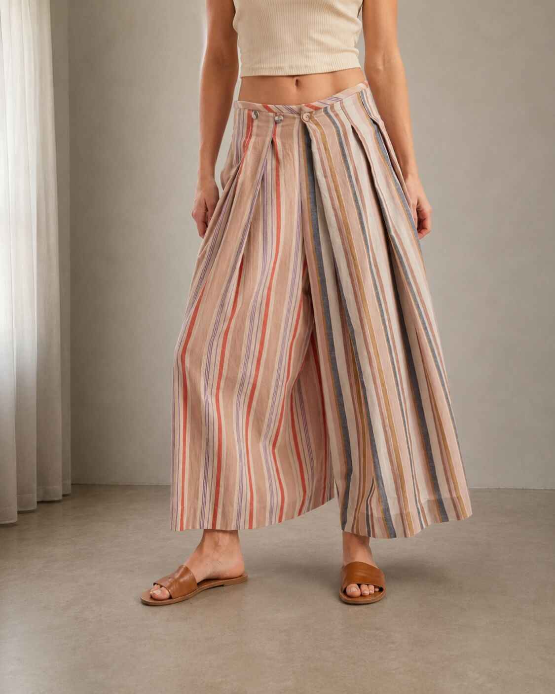 Multi-Stripe Pleated Front Wide-Leg Pants featuring a loose culotte-inspired cut with vertical stripe accents and structured pleat detailing, styled with minimal sandals in a softly lit interior space, highlighting the lightweight feel and flowing silhouette.