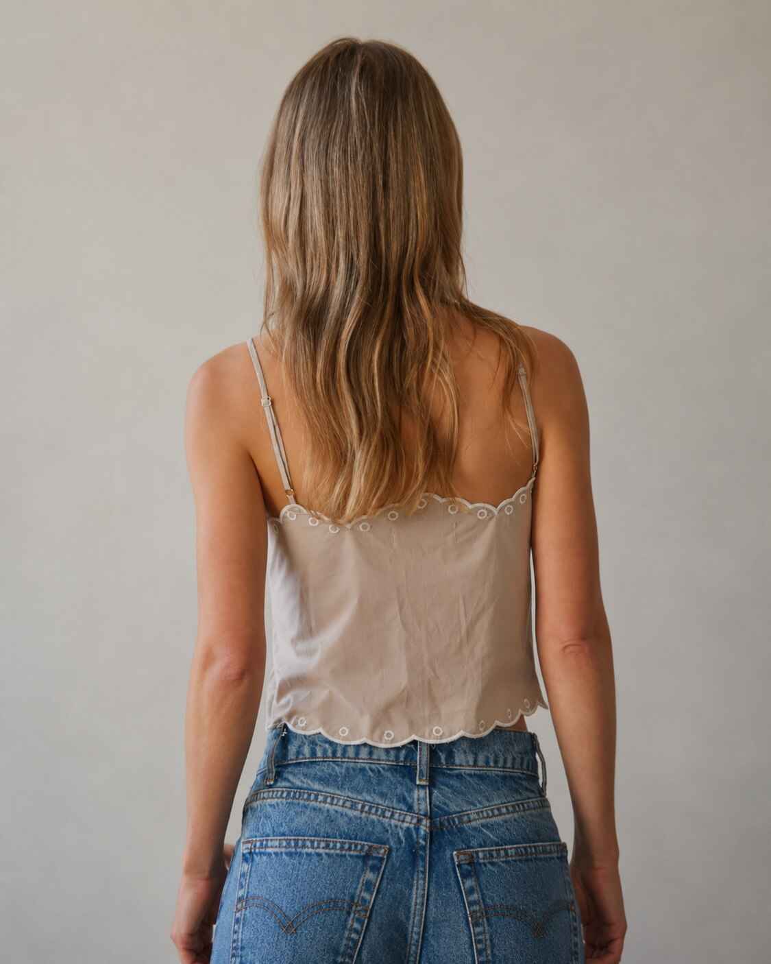 Floral Lace Work Sleeveless Top featuring adjustable spaghetti straps with scallop edge detailing and a soft woven finish, shown from the back with relaxed denim styling in a neutral studio space, highlighting the clean back silhouette and lightweight everyday comfort.