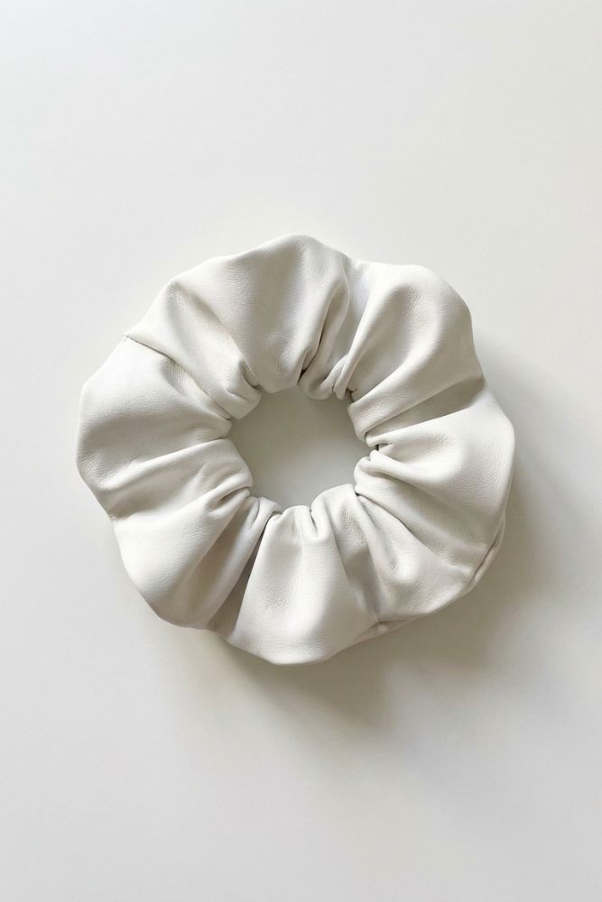 Single ivory faux leather scrunchie shown in close-up on a white background, emphasizing its soft, smooth texture and voluminous gathered design.
