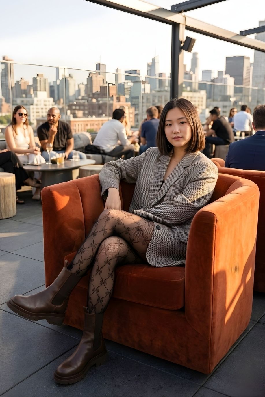 Fishnet Bow Tights featuring a sheer black bow pattern with stretch fit and textured fishnet look, styled with a blazer and boots on a rooftop lounge.