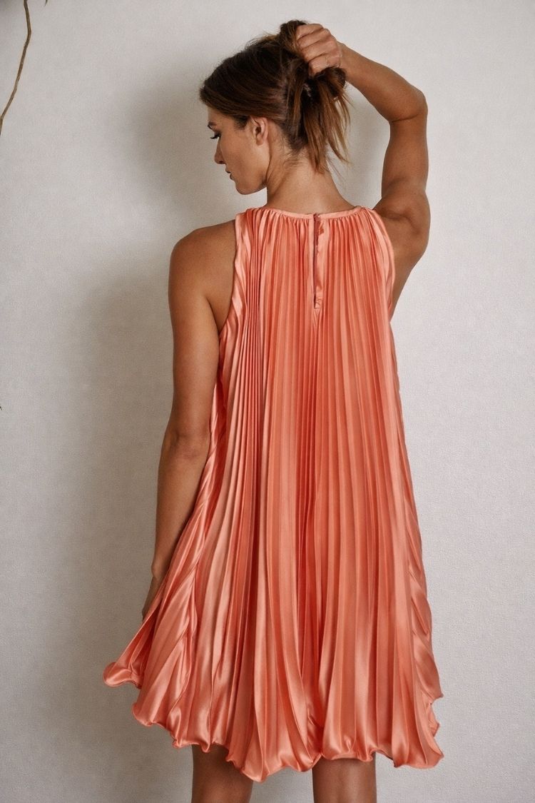 Woman in sleeveless coral pleated dress from Love Classic, high-quality fashion style