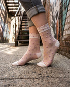 Blushing Hearts Sheer Socks featuring sheer ankle socks with raised pastel heart accents and soft toe panels, worn outdoors in an urban walkway setting, highlighting the delicate transparent texture and playful dotted heart detailing.