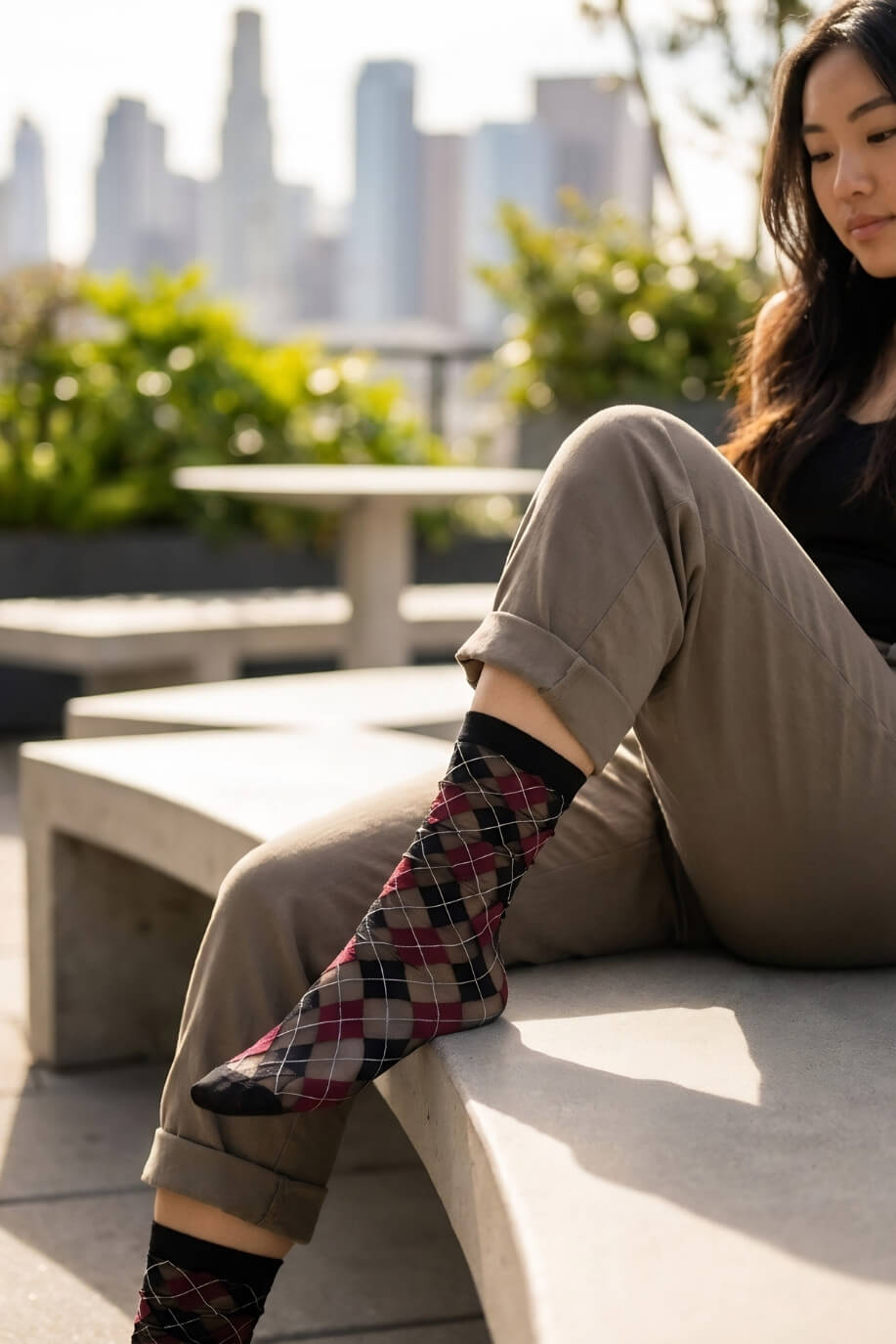 Sheer Argyle Crew Socks in black, red, and beige with a bold diamond pattern, worn with cropped trousers and leather loafers in an urban outdoor setting, emphasizing the breathable mesh and vibrant argyle design.