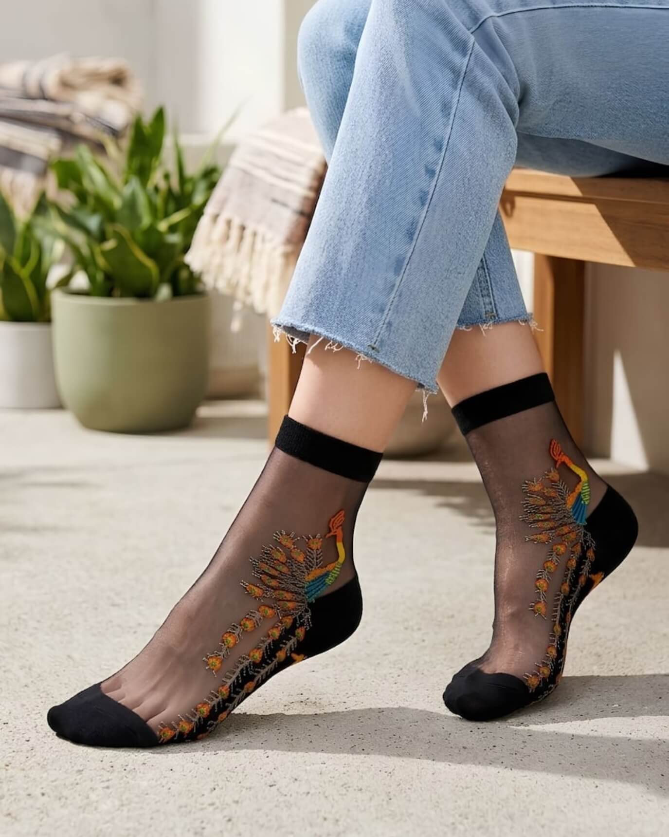 4-Pack Peacock Sheer Mesh Socks featuring transparent black mesh fabric with intricate peacock embroidery and soft stretch cuffs, worn with cropped denim jeans in a sunlit indoor setting, highlighting the delicate texture and eye-catching artistic finish.