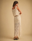 Crochet Knitted Skirt featuring a full length floral crochet pattern with a sleeveless layered back and scalloped edges, captured from the back in a relaxed standing pose with chunky woven sandals against a minimal neutral backdrop, highlighting handcrafted texture and flowy structure.
