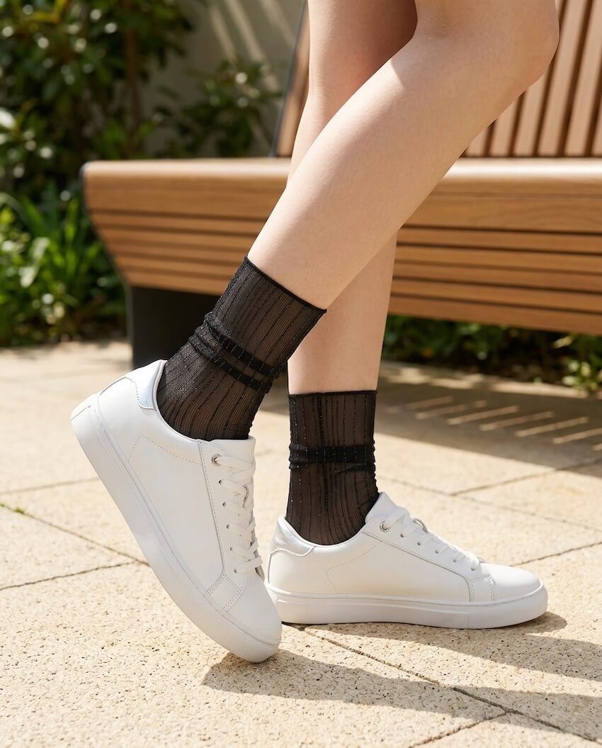 Sparkle Pinstripe Sheer Socks featuring translucent mesh fabric with glitter pinstripe detailing and a flexible crew length fit, worn with white sneakers in a sunlit outdoor setting, highlighting breathable comfort and stylish casual layering.