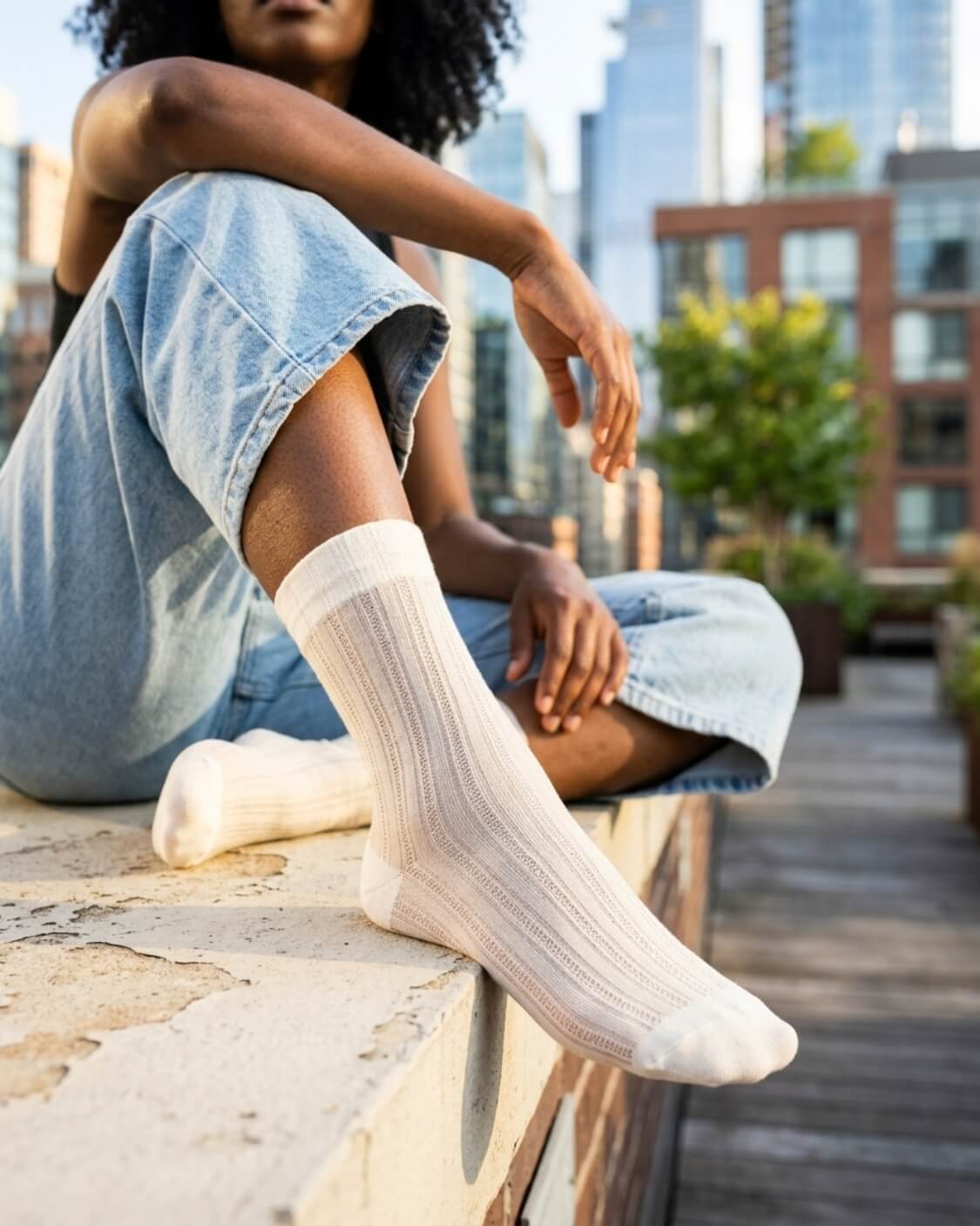5-Pack Soft Horizon Sheer Socks featuring a delicate sheer ribbed knit with a classic crew length, worn with relaxed denim while seated on a rooftop ledge, highlighting lightweight comfort and an airy finish.