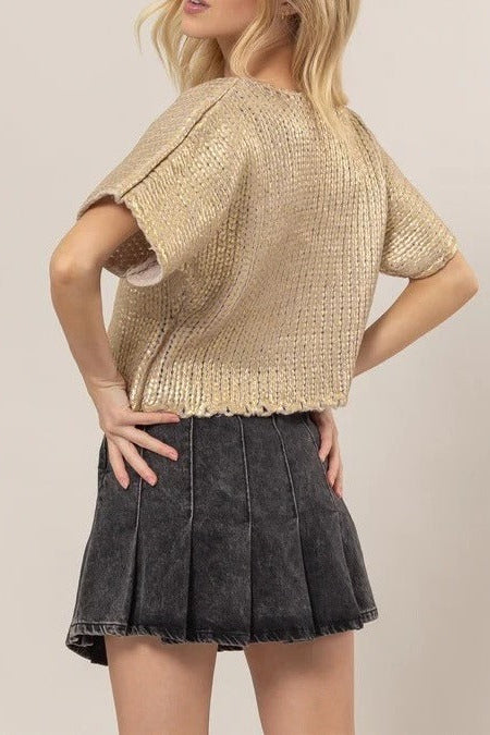 Model showcasing the gold Metal Coated Knit Sweater designed with a classic round neck, shimmering knit surface, and delicate lettuce-edge trim.