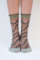 Sheer socks with criss-cross pattern worn by a person on a white background