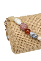 Close-up of the natural Rachel Straw Clutch showcasing the detailed straw weave, sculptural bead embellishments, and secure zip-top finish.