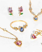 Blossoming Tulip Studs featuring pink crystal tulip earrings displayed alongside coordinating gemstone rings and necklaces on a bright reflective surface, highlighting delicate sparkle and romantic floral jewelry styling.