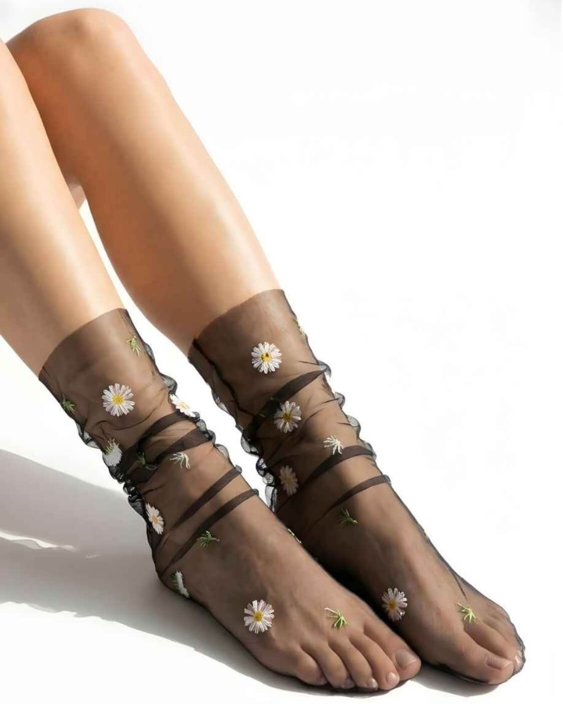 Sheer Garden Daisy Crew Socks in black sheer mesh with white and yellow daisy embroidery, displayed on feet to emphasize contrast and pattern.