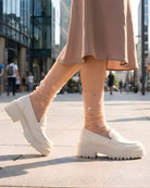 Sheer Garden Daisy Crew Socks in nude with daisy embroidery, styled with white platform loafers in an outdoor city setting for a casual look.