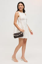 Model carrying the chocolate Rachel Straw Clutch crafted with woven straw texture, faceted beads, polished hardware, and versatile detachable chain.